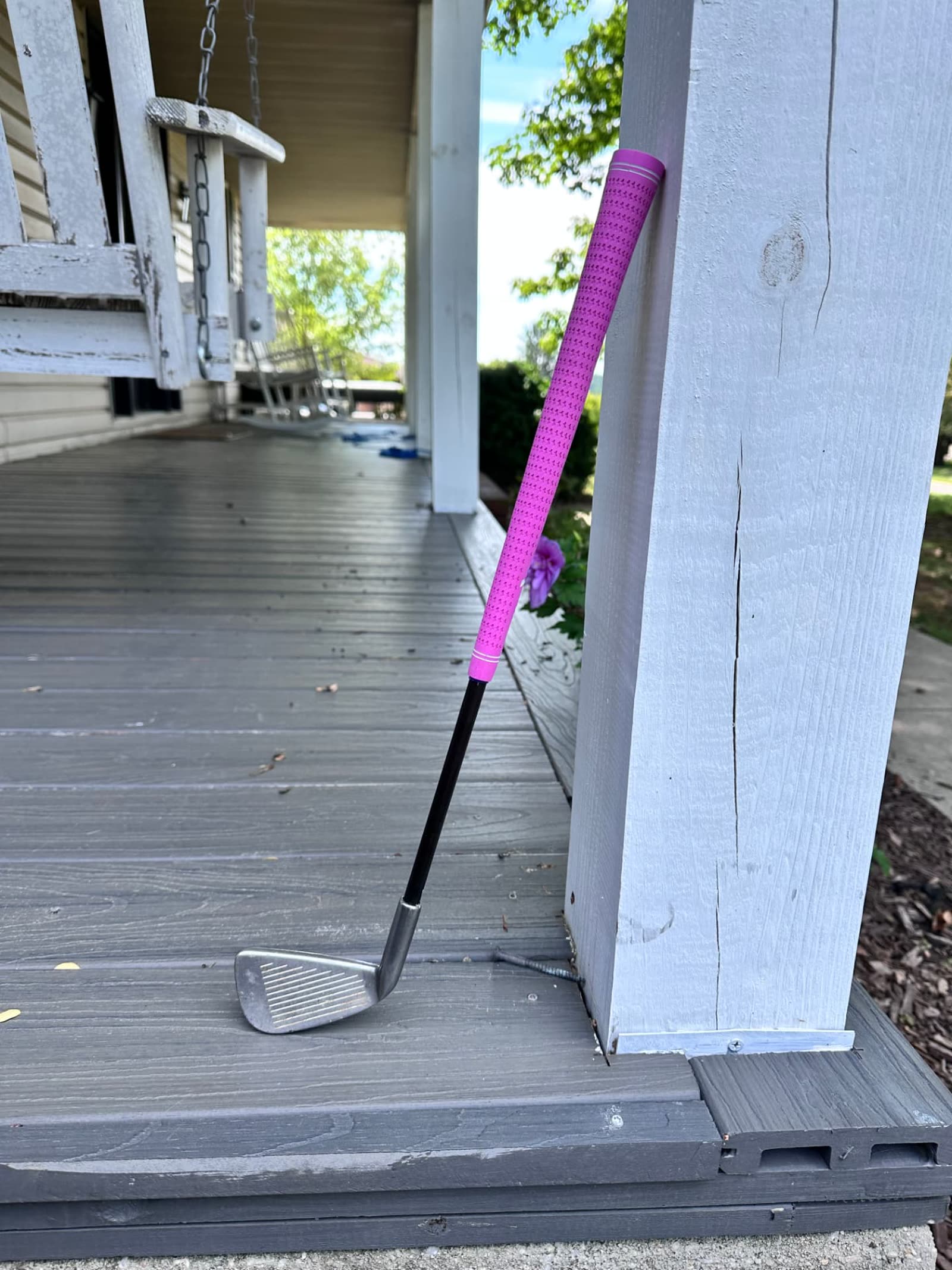 The Nibbler N18 prototype, a short iron with a magenta grip, leaning against a painted porch post.
